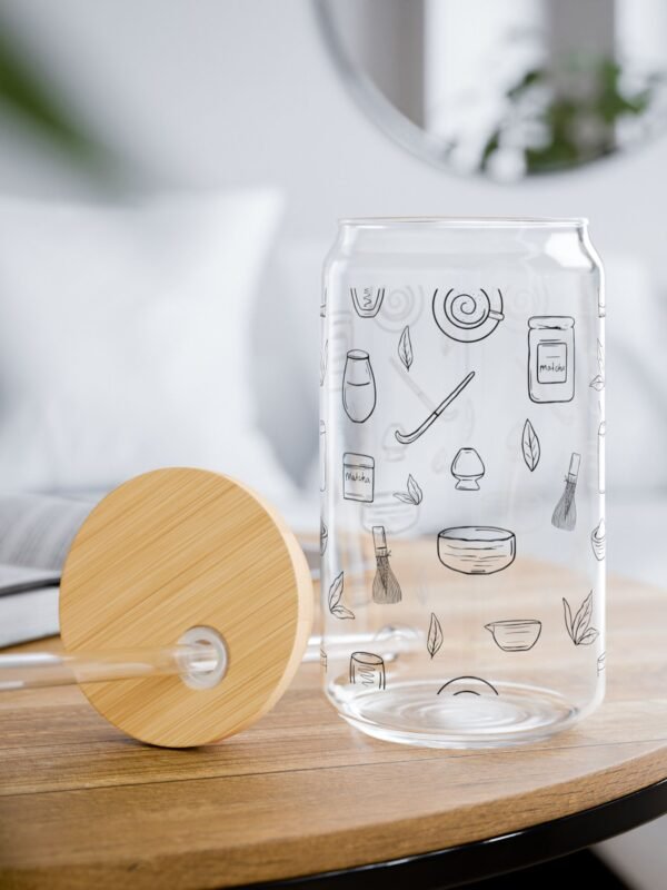 Clear glass tumbler with bamboo lid and straw, decorated with matcha-themed illustrations including matcha drinks, spoon, whisks, mug, and matcha leaves.