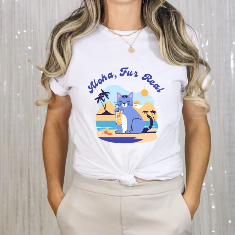 A white Cotton unisex t shirt with a cat drinking cocktail on the beach surrounded with palm trees and sun. Bold phrase of Aloha Fur Real above the cat