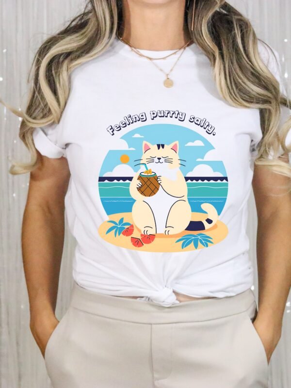 White color T-shirt with the phrase ‘Feeling purrty salty’ printed above a cat drinking pina-colada on the beach relaxing illustration