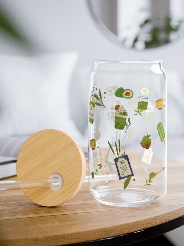 Clear glass tumbler with bamboo lid and straw, decorated with matcha-themed illustrations including matcha drinks, spoon, whisks, mug, and matcha leaves.