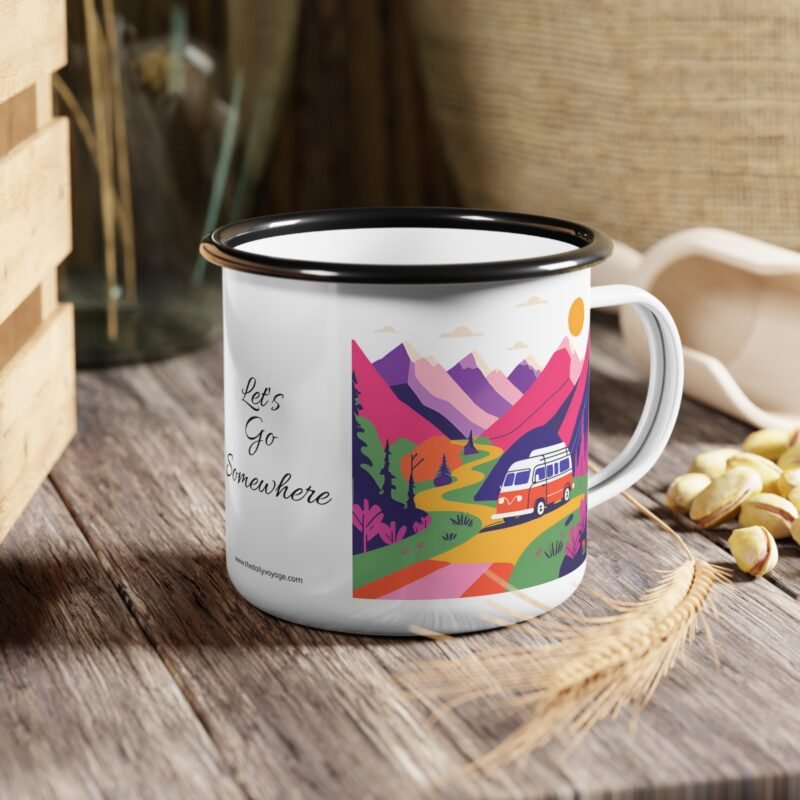 Colorful enamel mug with a camper van and mountain scene design placed on a wooden picnic table at a forest campsite during sunrise.