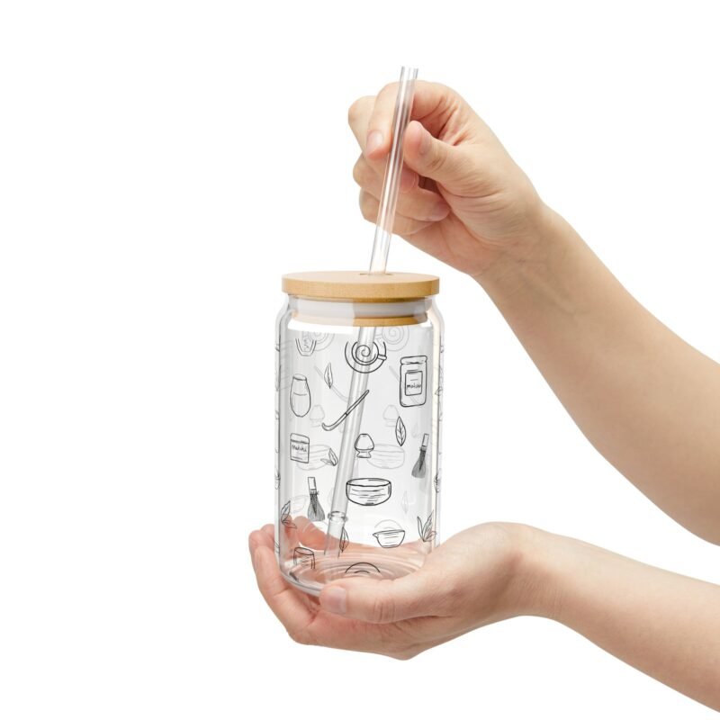 Clear glass tumbler with bamboo lid and straw, decorated with matcha-themed illustrations including matcha drinks, spoon, whisks, mug, and matcha leaves.