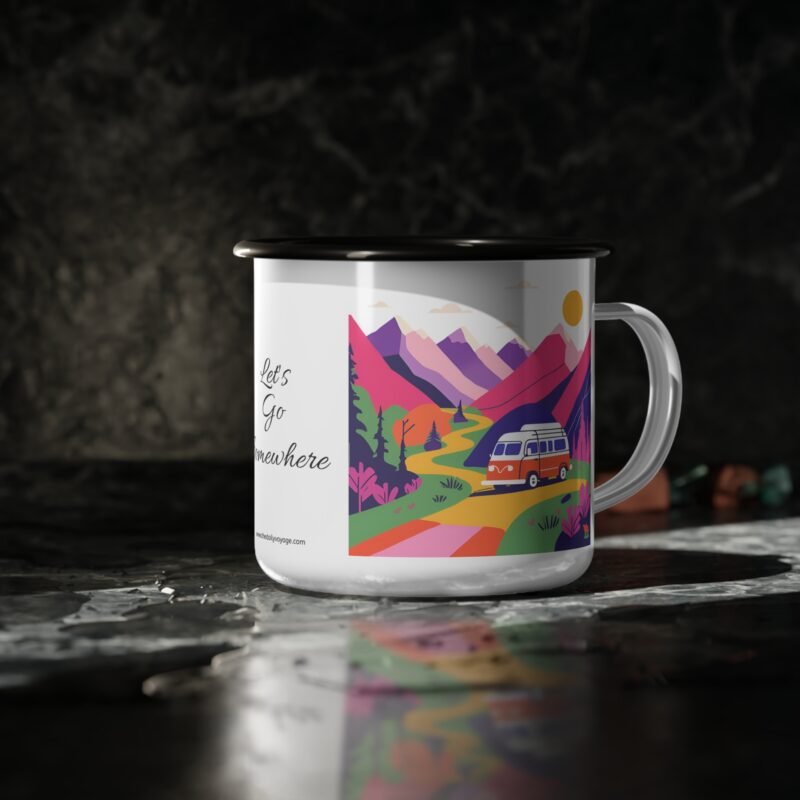 Colorful enamel mug with a camper van and mountain scene design placed on a wooden picnic table at a forest campsite during sunrise.