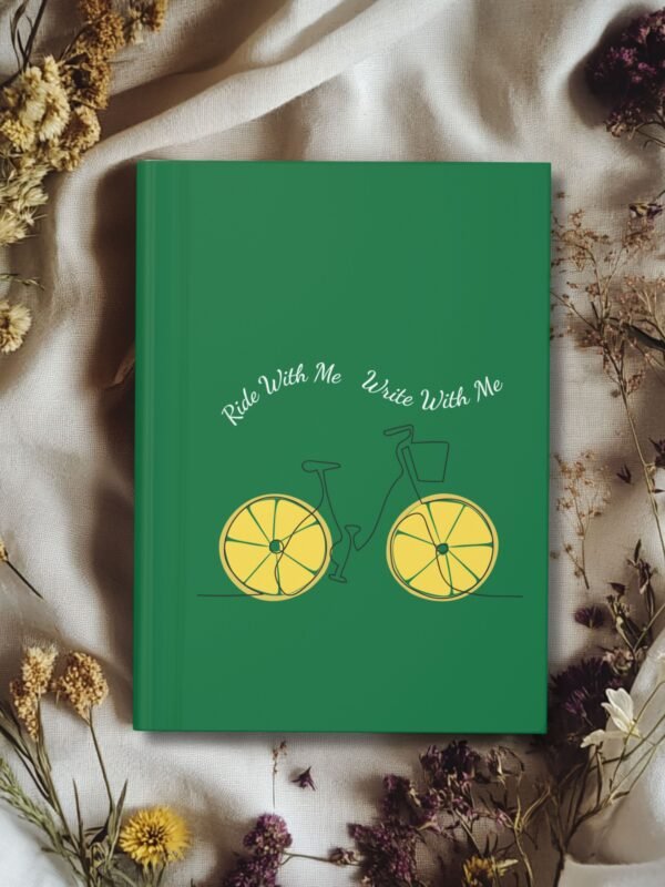Green hardcover journal with a minimalist bicycle illustration featuring lemon slice wheels and the phrase ‘Ride With Me Write With Me’ above it.