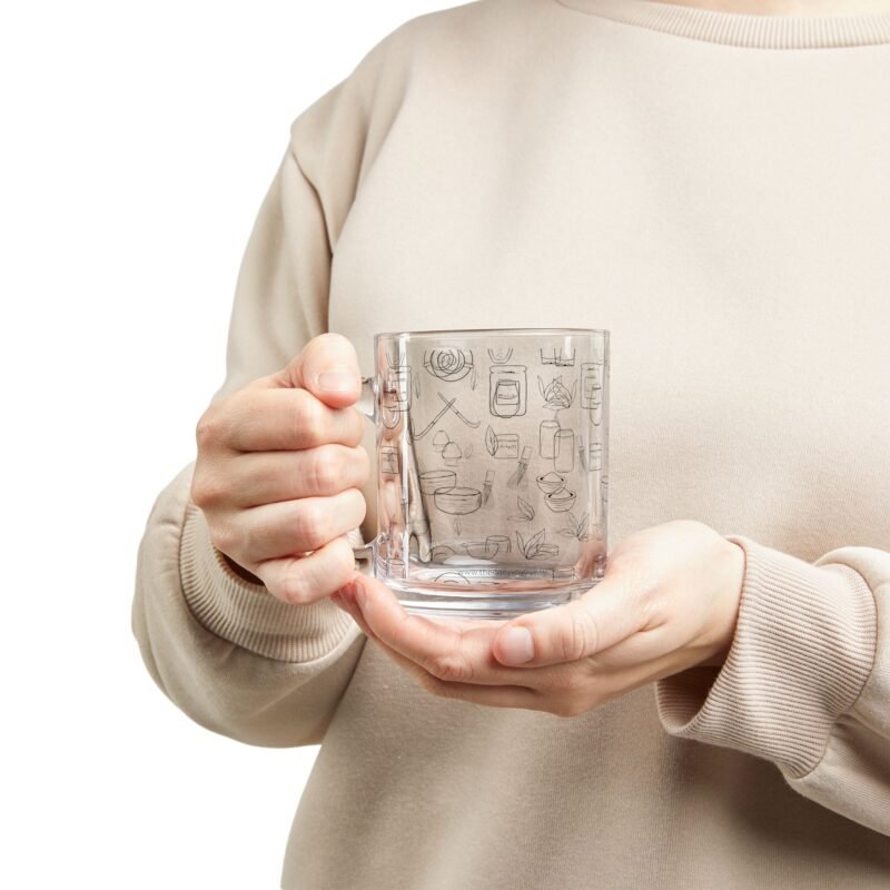 Clear glass mug decorated with matcha-themed illustrations including matcha drinks, spoon, whisks, mug, matcha powder, bamboo tea spoon and matcha leaves.