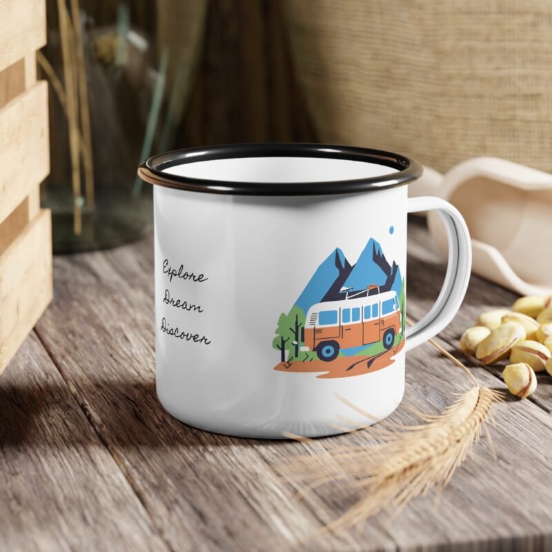 Colorful enamel mug with a camper van and mountain scene design placed on a wooden table at a forest campsite during sunrise.