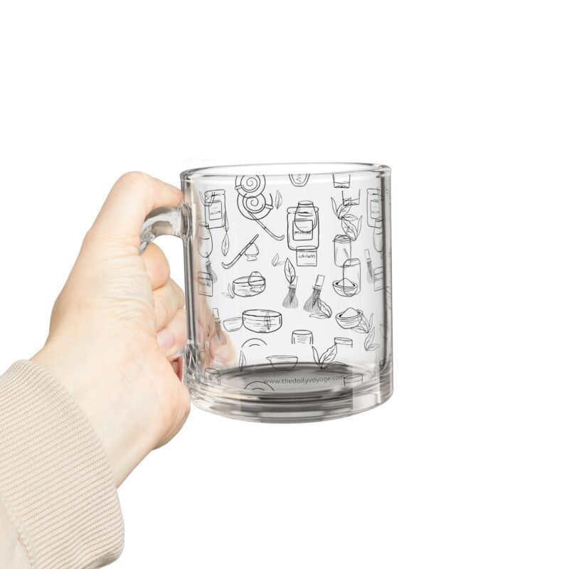 Clear glass mug decorated with matcha-themed illustrations including matcha drinks, spoon, whisks, mug, matcha powder, bamboo tea spoon and matcha leaves.