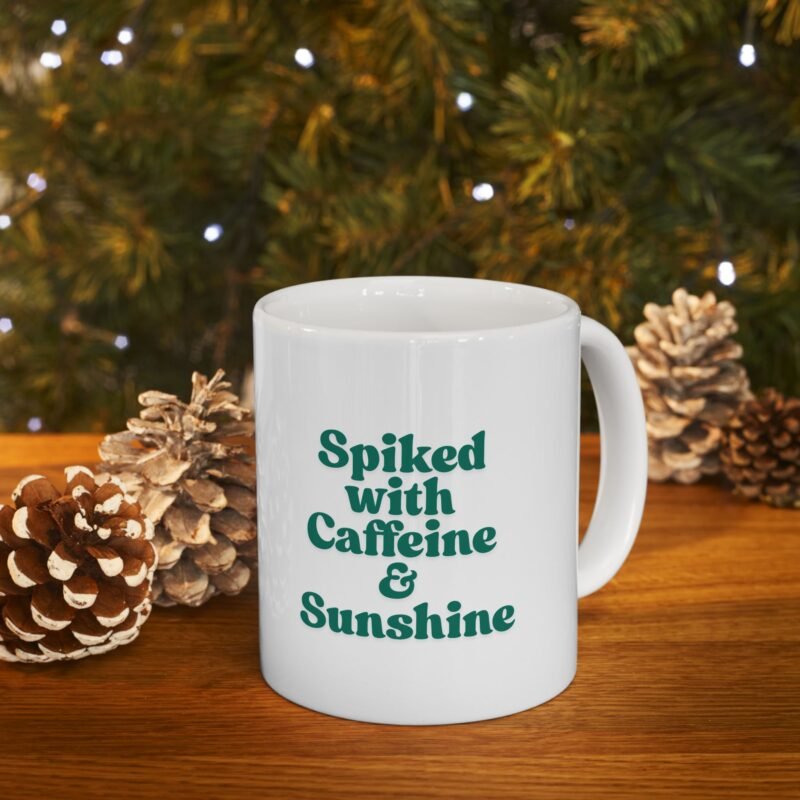 A ceramic mug features a sunny bright festive cactus illustration and writing of spiked with caffeine and sunshine