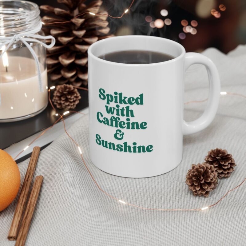 A ceramic mug features a sunny bright festive cactus illustration and writing of spiked with caffeine and sunshine