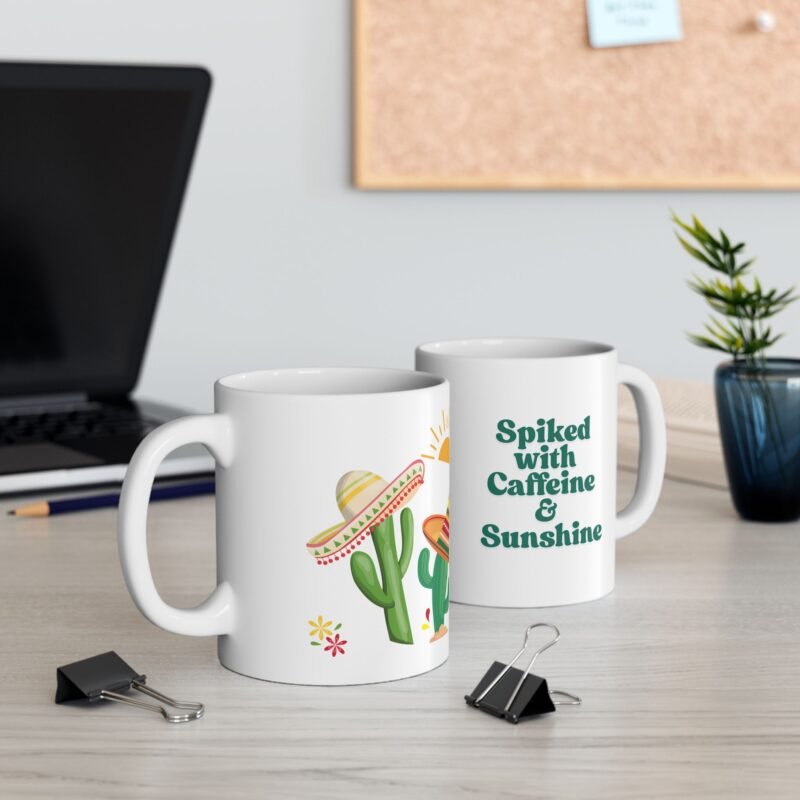 A ceramic mug features a sunny bright festive cactus illustration and writing of spiked with caffeine and sunshine