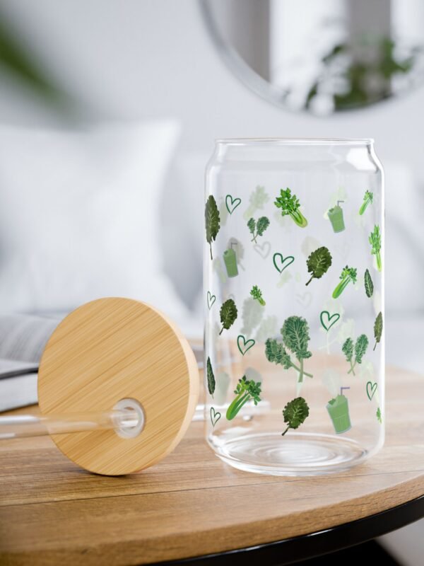 Glass tumbler with green kale and smoothie illustrations, bamboo lid, and clear straw on white background
